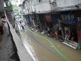 people sitting next to a flooded alley in Hunan