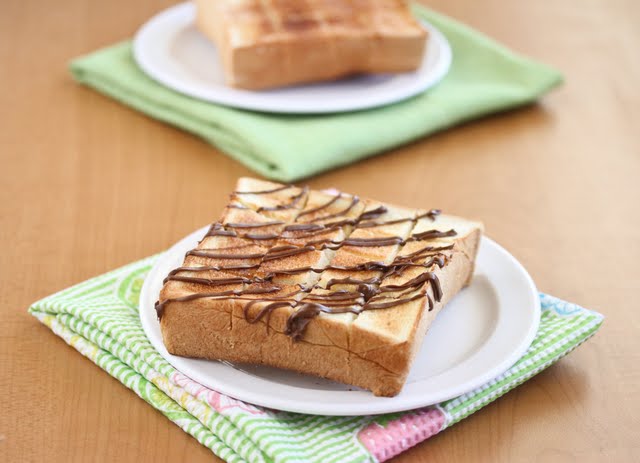 brick toast drizzled with chocolate on a white plate with a plain brick toast in the backgroun