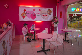 cafe with pink seats / heart tables and a sign on the wall saying "Power of Crepe is Power of Love"
