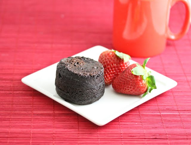 flourless chocolate cake on a plate with fresh strawberries