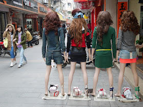 two young women walking past mannequins in Yangjiang, China
