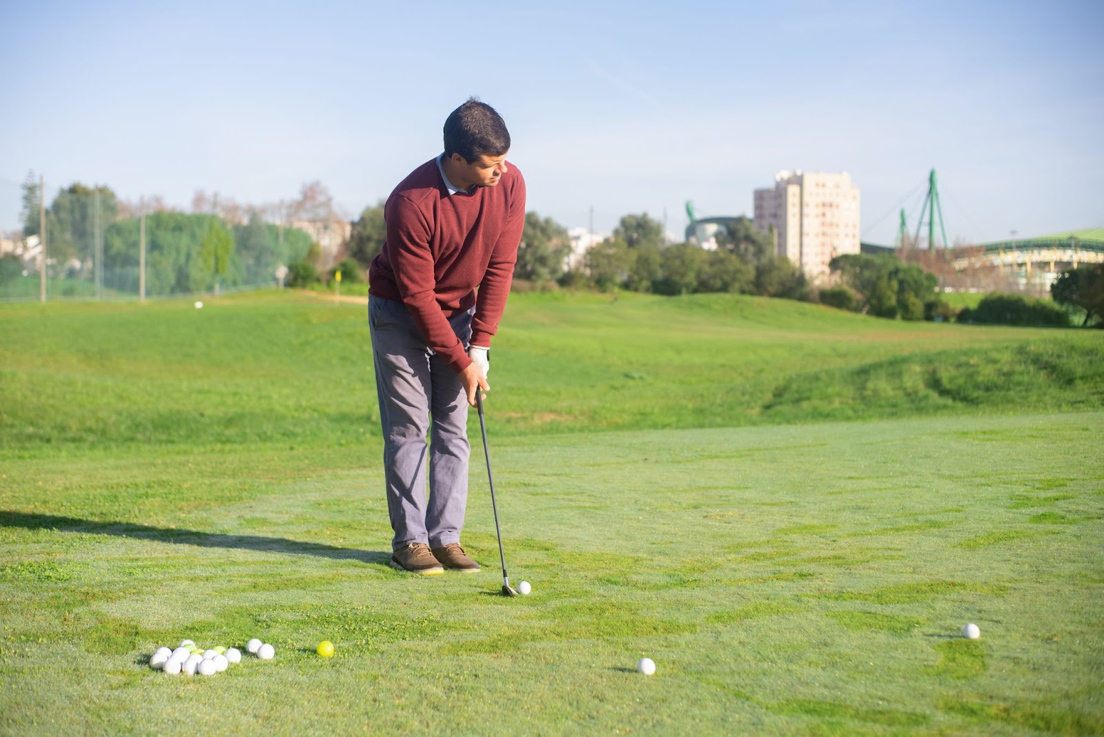 older golfer in red shirt practicing chipping