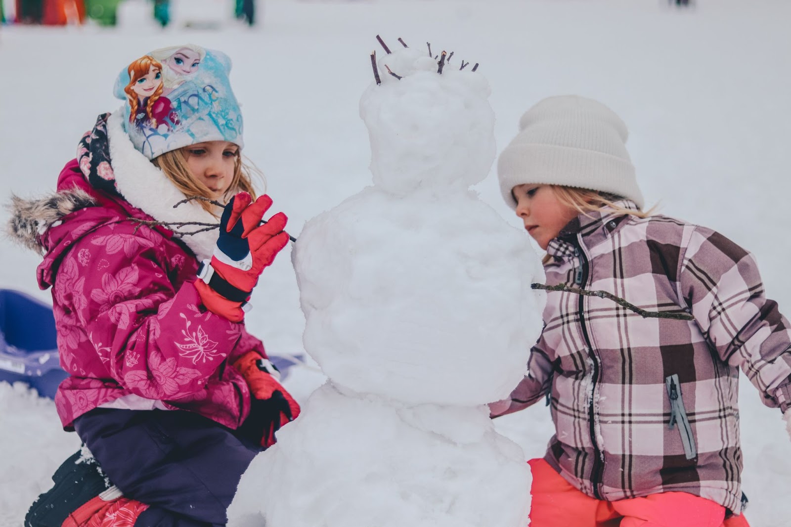 Kids playing in the winter, making a snow man. 