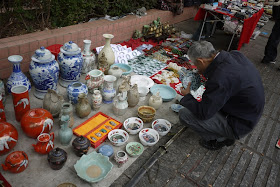 man closely examining a vase outside Tianxinge Antique City in Changsha, China