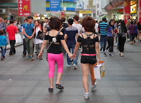 young women wear black a hot pink outfits and holding hands