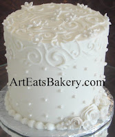 Tall tier white butter cream romantic elegant wedding cake with royal icing curlicues, sugar pearls and edible flowers design