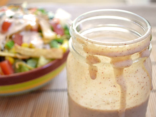 taco ranch dressing in mason jar with bowl of salad in background 