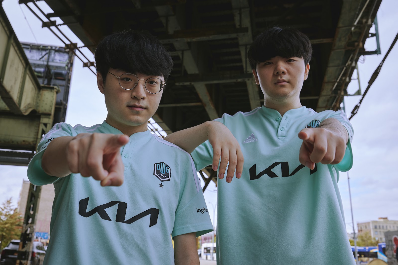A promotional photo showing Damwon mid laner Showmaker and jungler Canyon in their jerseys, pointing at the camera. 