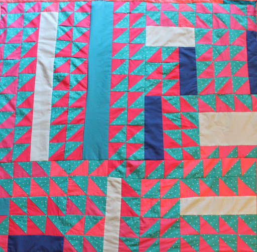 a quilt made of lots of pink and blue triangles