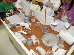 Children scoop, pour, and measure dry sand in a sensory table.