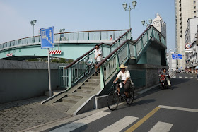 man walking bike down ramp on pedestrian bridge in Shanghai