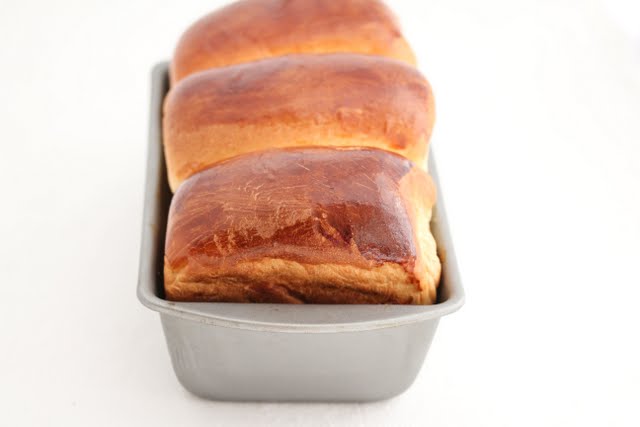 golden brown hokkaido milk toast loaf in a baking pan