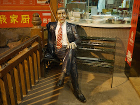 A Barack Obama statue sitting on a bench