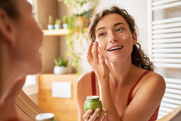 Woman applying moisturiser on face during morning routine  skin lotion stock pictures, royalty-free photos & images