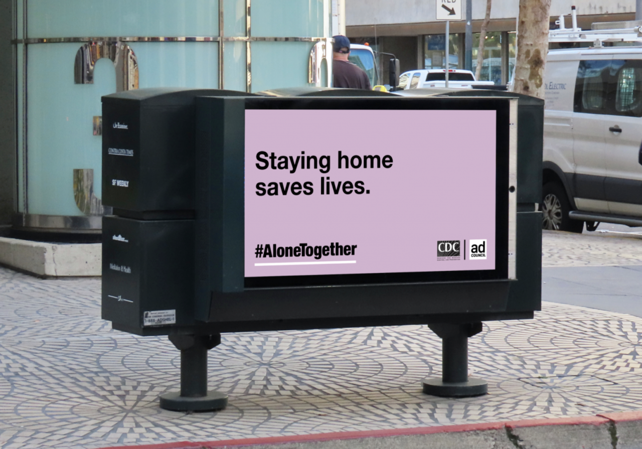 Billboard with light purple background and black text "Staying home saves lives." and the hashtag #AloneTogether