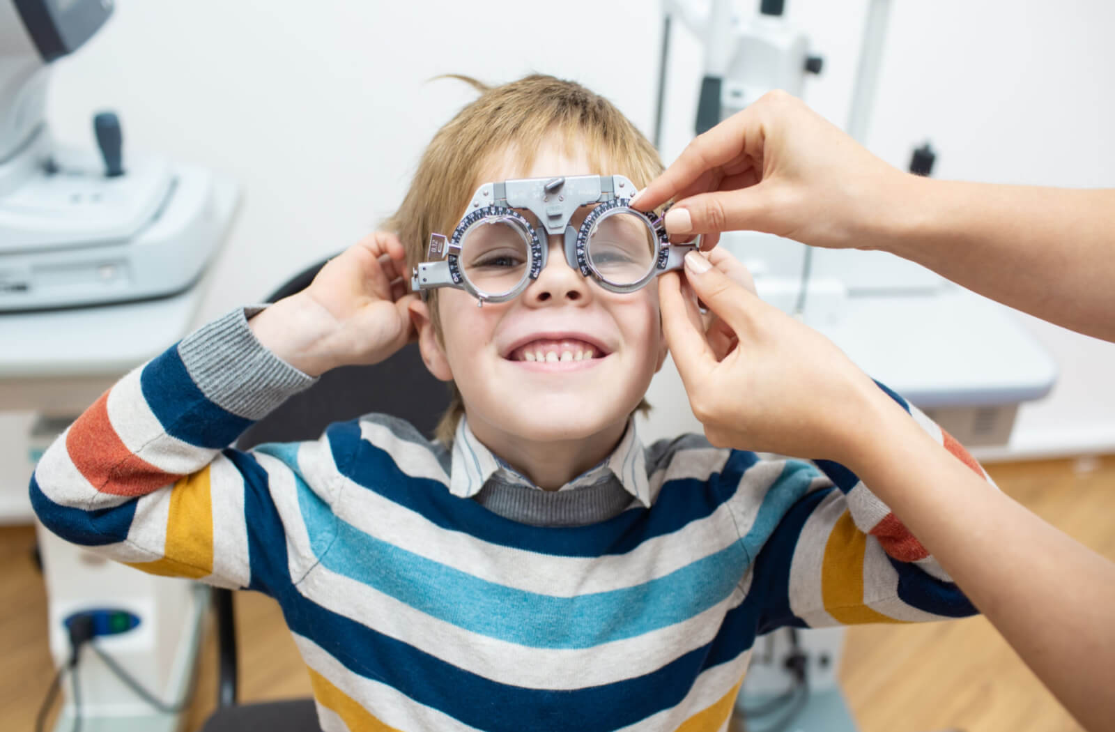 a smiling child has an eye exam done by an optometrist