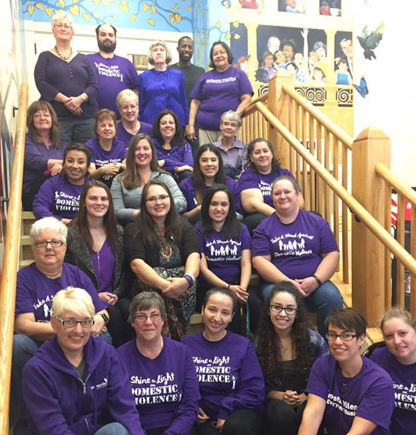 group of community crisis center volunteers in purple shirts sitting on stairs