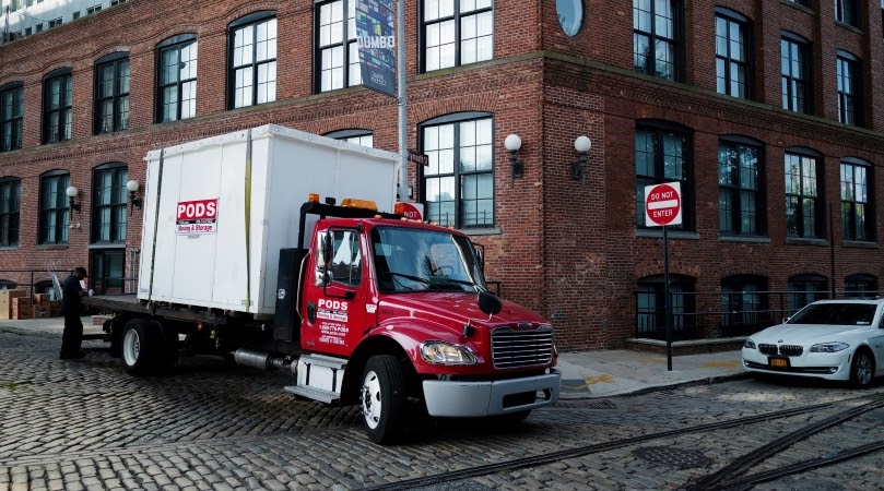 PODS truck delivering a portable storage container in a big city