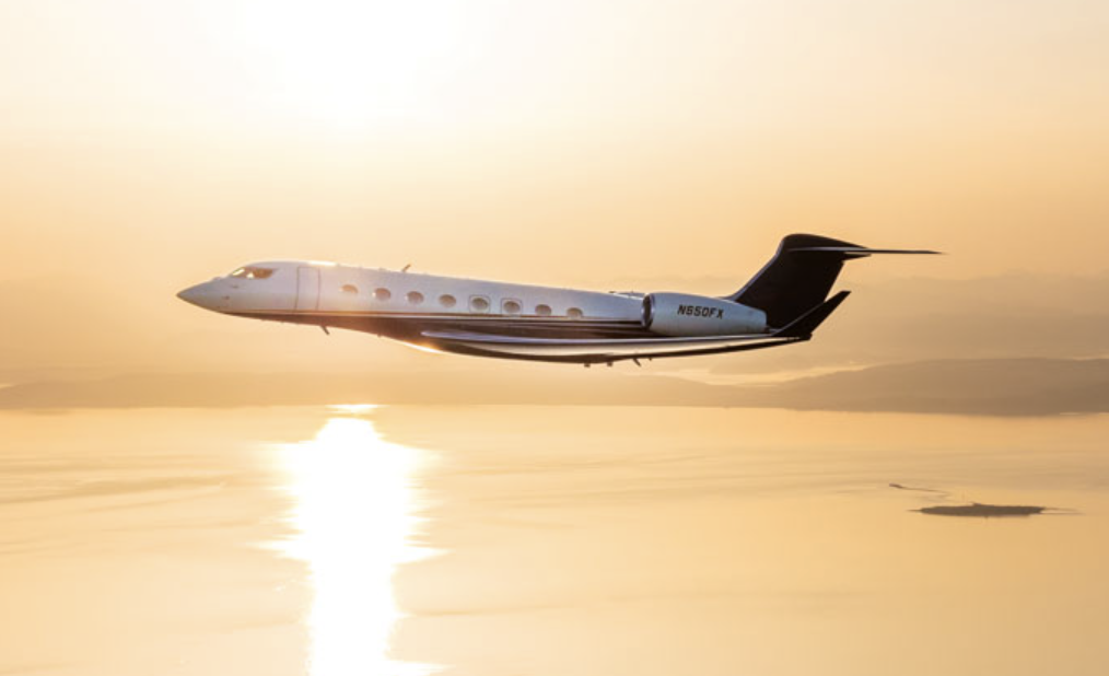 Flexjet vs. NetJets - A plane flies over water with sunlight reflecting off of it.