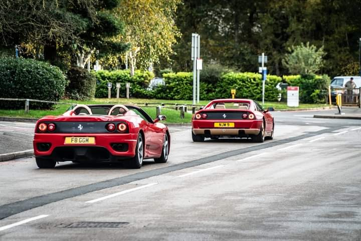 Two red sports cars on a road  Description automatically generated with medium confidence