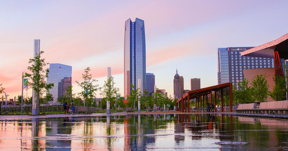 Oklahoma City skyline reflected by water in a purple-pink sunset