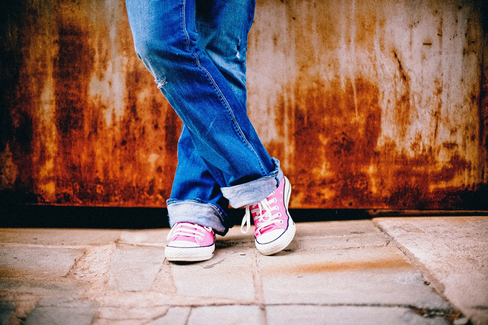 Legs of a person in jeans and pink Converse shoes