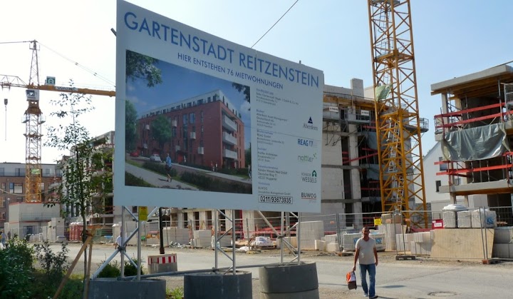 Großbaustelle, Schild: »Gartenstadt Reitzenstein. Hier entstehen 76 Mietwohnungen…«.