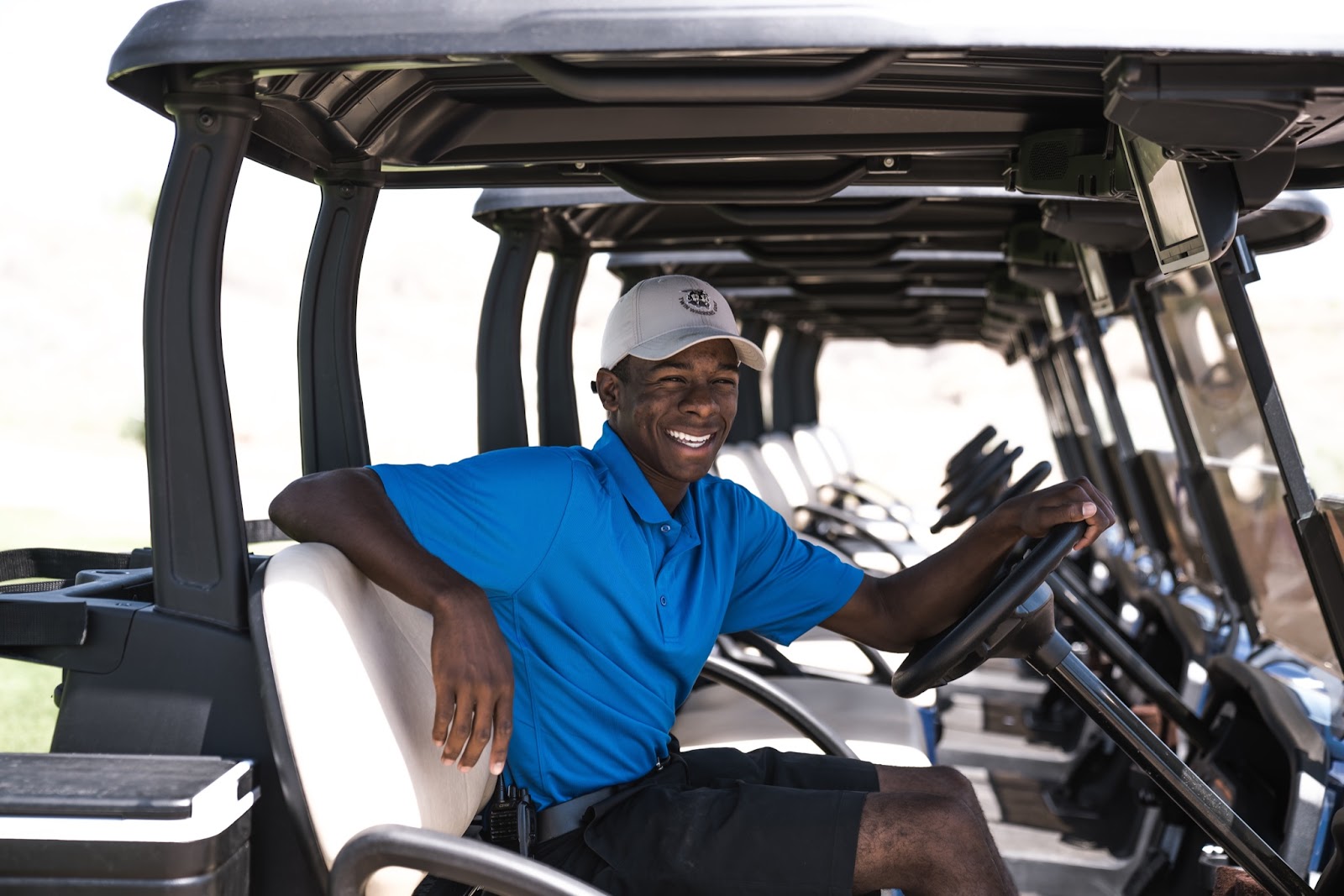 smiling man in blue shirt on golf cart