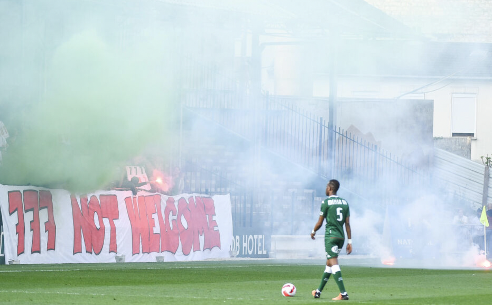 A football player on a field with a ball and smoke

Description automatically generated with low confidence