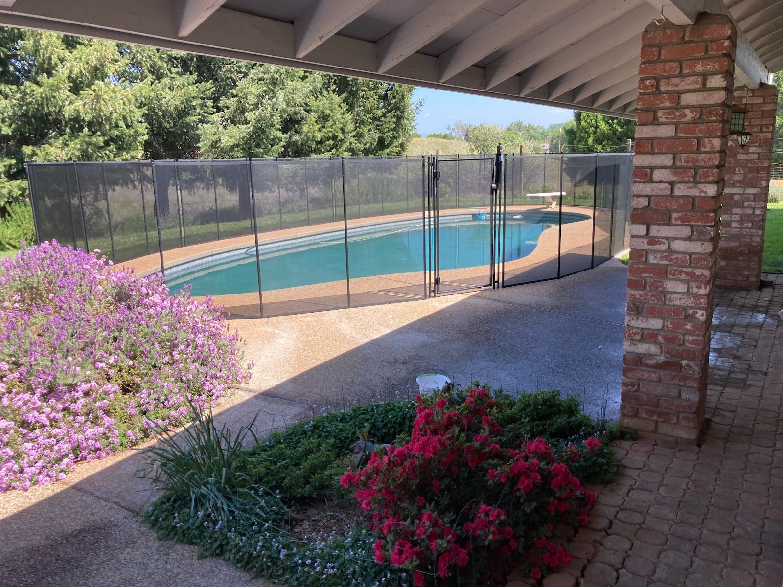 Black mesh pool fencing installed around a backyard pool