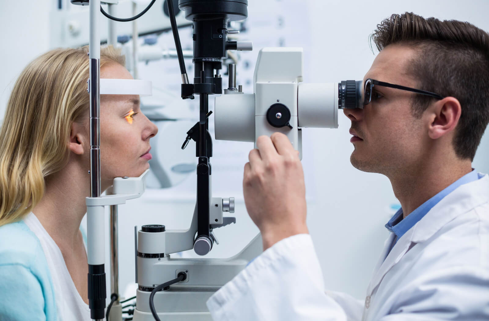 An optometrist performing a slit-lamp exam on his patient.