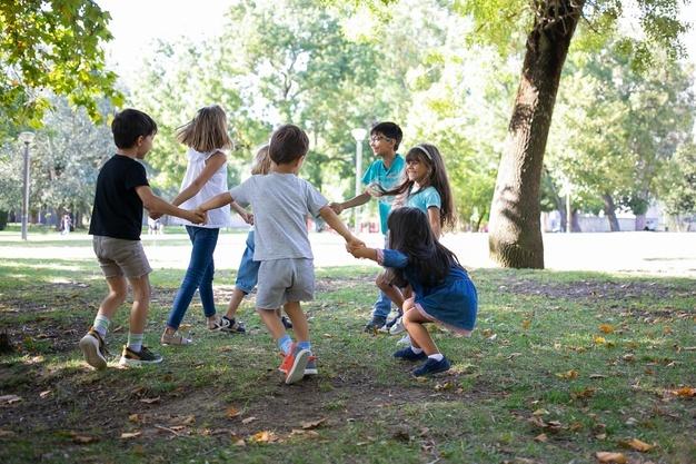 Crianças felizes brincando juntas ao ar livre, dançando na grama, desfrutando de atividades ao ar livre e se divertindo no parque. festa infantil ou conceito de amizade Foto gratuita