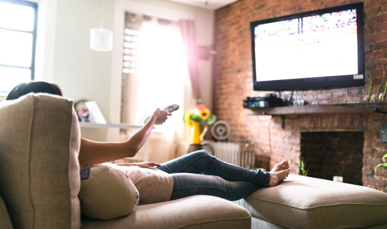 A woman watching TV using a video streaming service