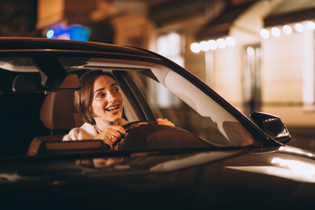 Mulher motorista de aplicativo dirigindo à noite