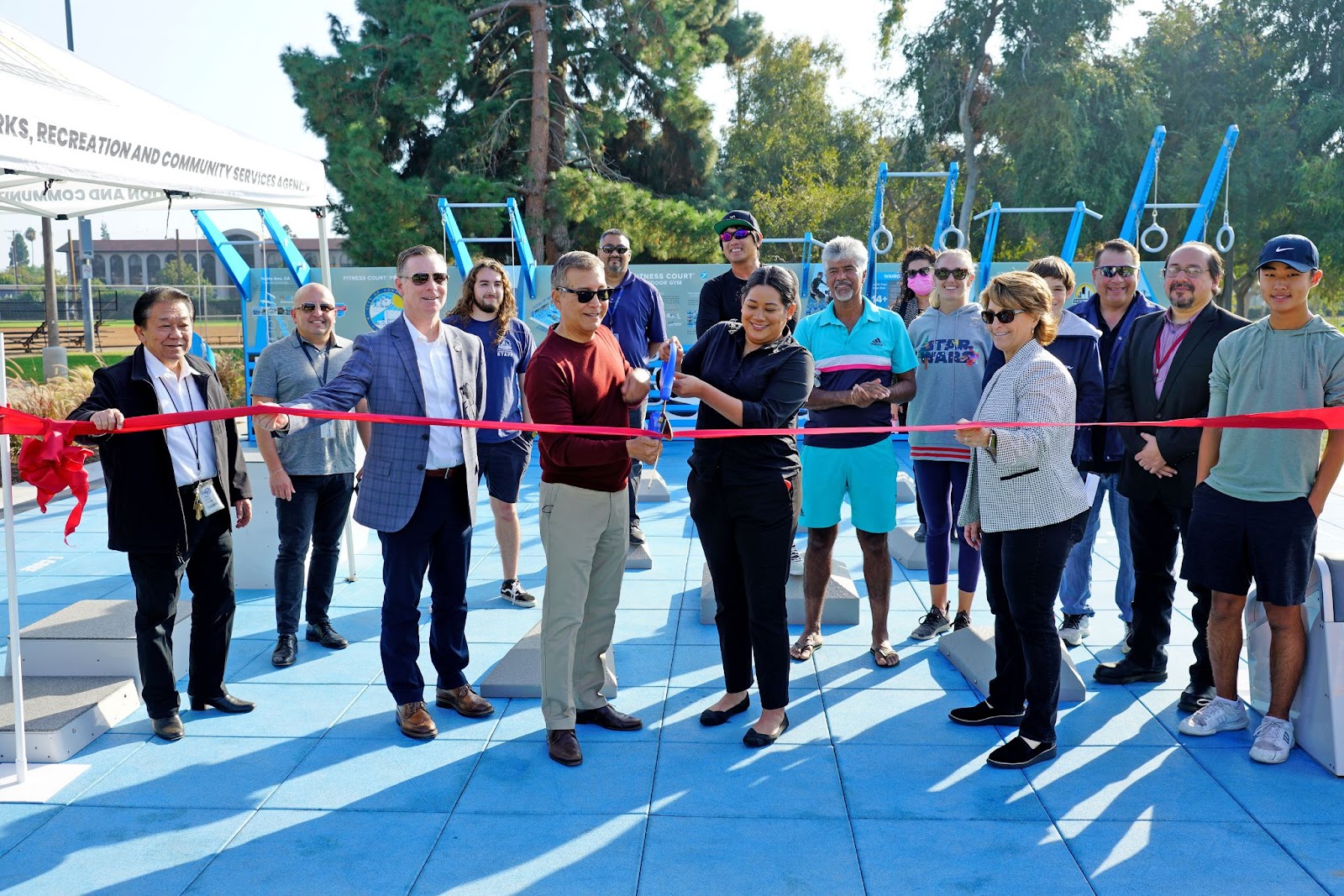 A group of City officials and residents stand at the Cabrillo fitness court as Councilmember Lopez and Mayor Sarmiento get ready to cut the ribbon.
