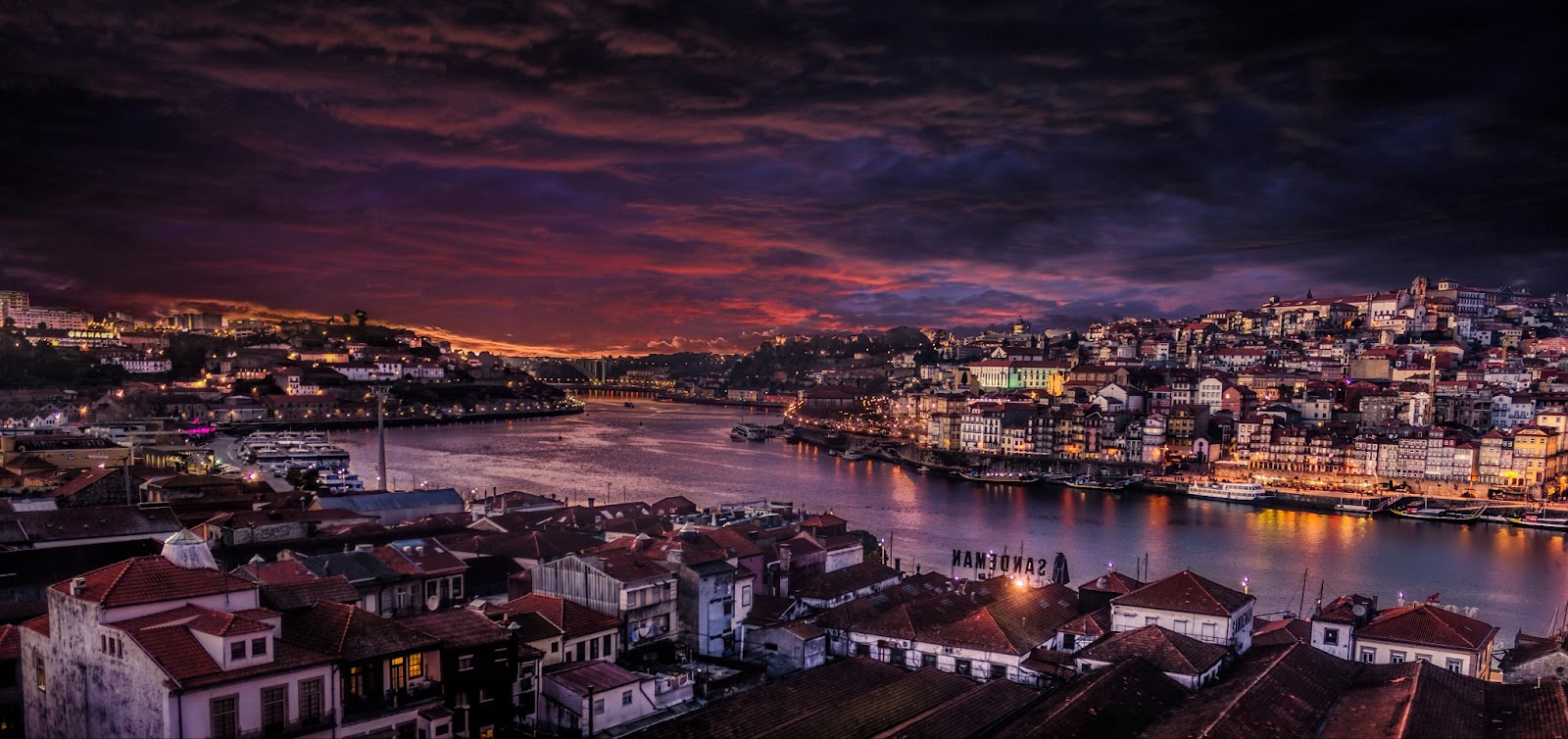 A picturesque riverside village on the Douro River during the evening hours, characterized by charming Portuguese houses reflecting in the calm waters.
