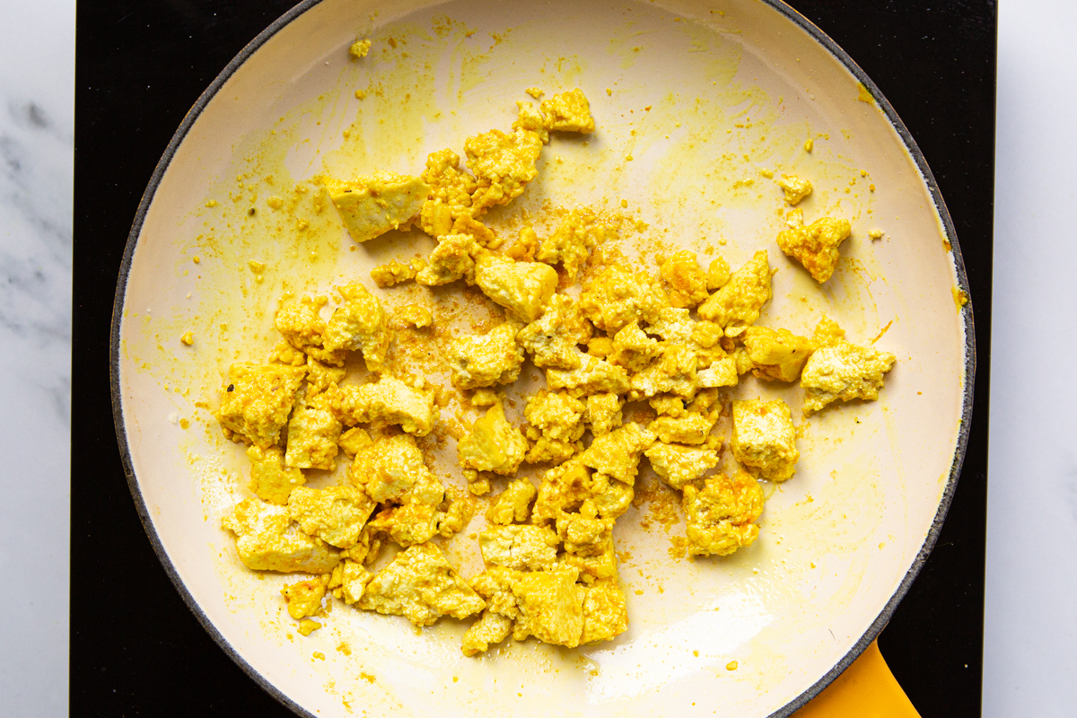 tofu scramble cooked with turmeric and nutritional yeast in a skillet