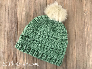 green crochet bead stitch hat lying flat on wooden background