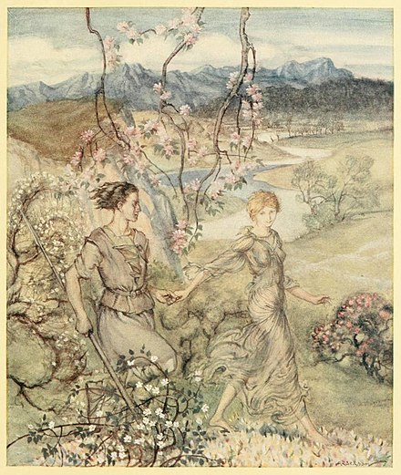 A young man and woman walk through a idyllic landscape with a river and mountain in the background.