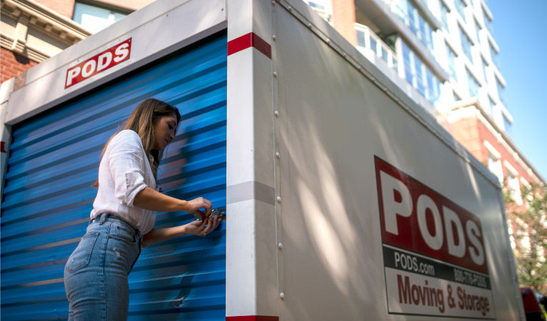 A woman is unlocking her PODS portable moving container which she is using for her move from Texas to California.