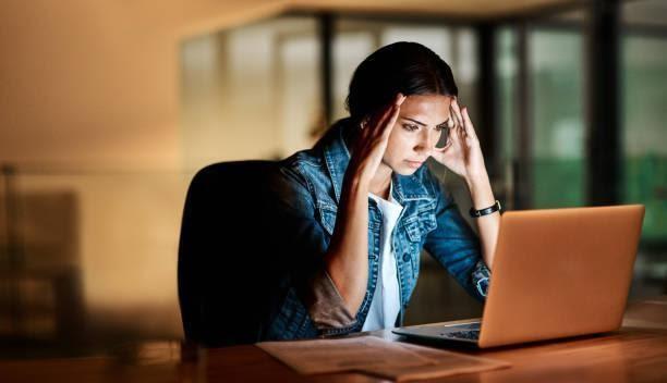 I'm under so much pressure go get this done Shot of a young businesswoman looking stressed while using her laptop in an office at night deadline stock pictures, royalty-free photos & images