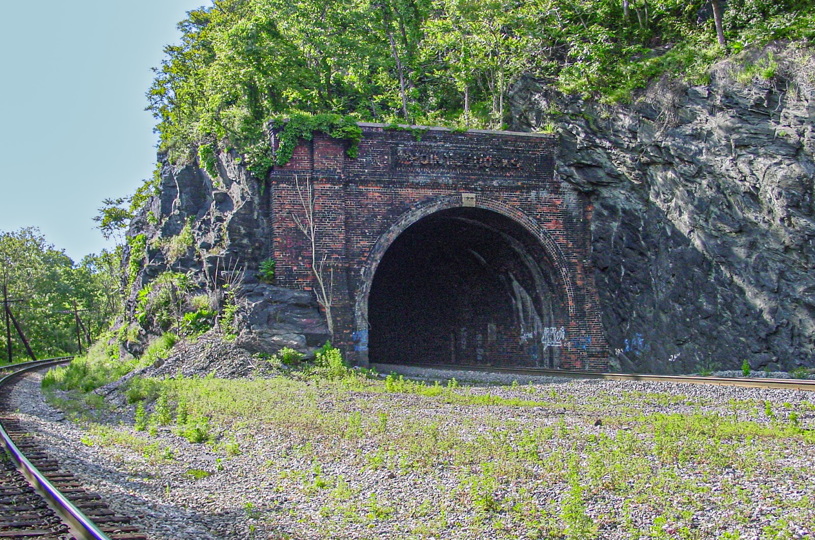 A rail road tunnel with a track into the tunnel and a track running to the side
