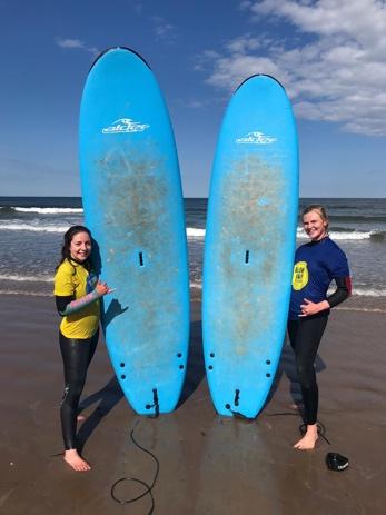 A person standing on a beach holding a surf board posing for the camera

Description automatically generated