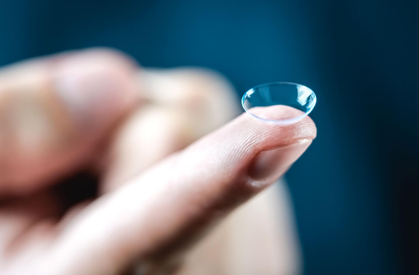 Multifocal contact lenses on the tip of an index finger.