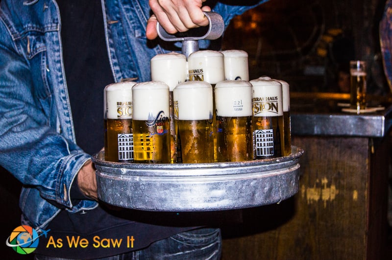 A waiter's hands holding a tray of beer glasses