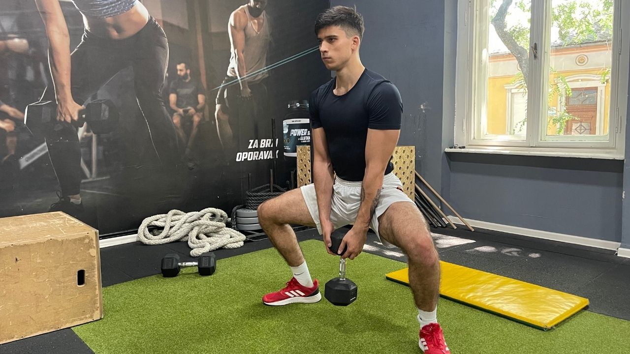 Vanja performs a sumo squat pull to press exercise.