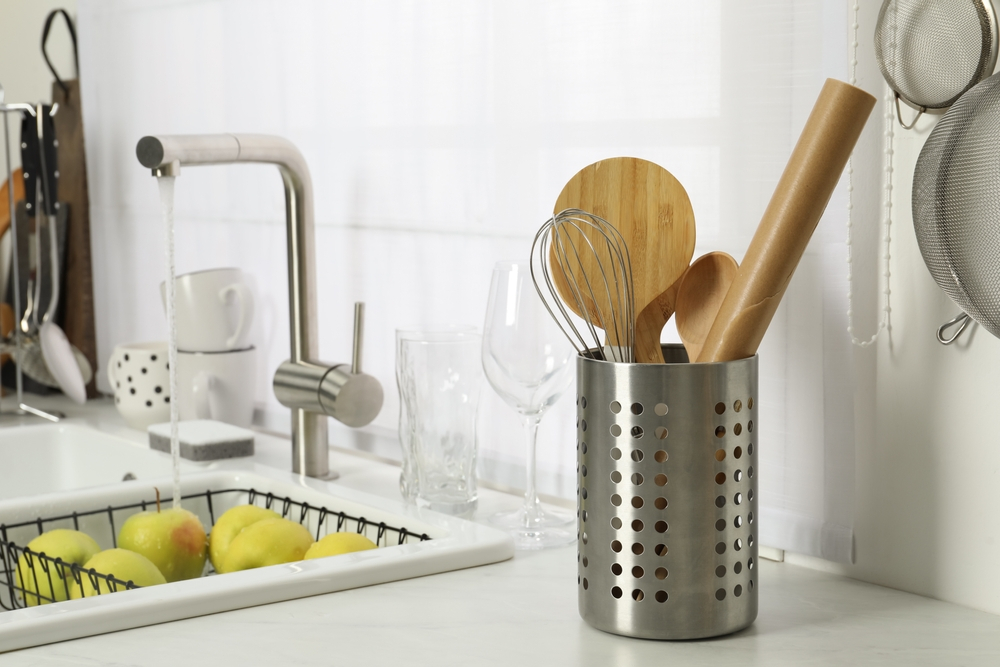 Utensils in metal holder on kitchen counter.