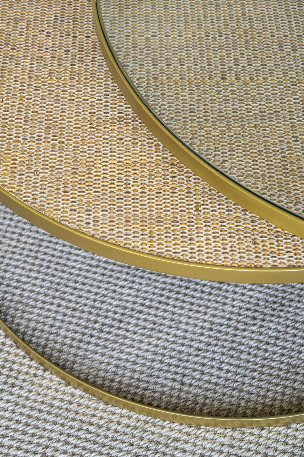 Close-up of a round, woven table surface with glass tops and brass edges.