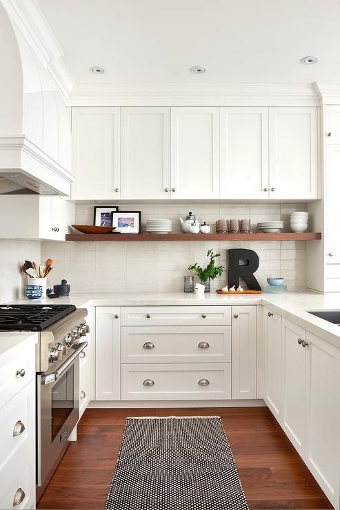 small u-shaped kitchen with white shaker cabinets, wood flooring, black and white runner rug and chrome cabinet hardware