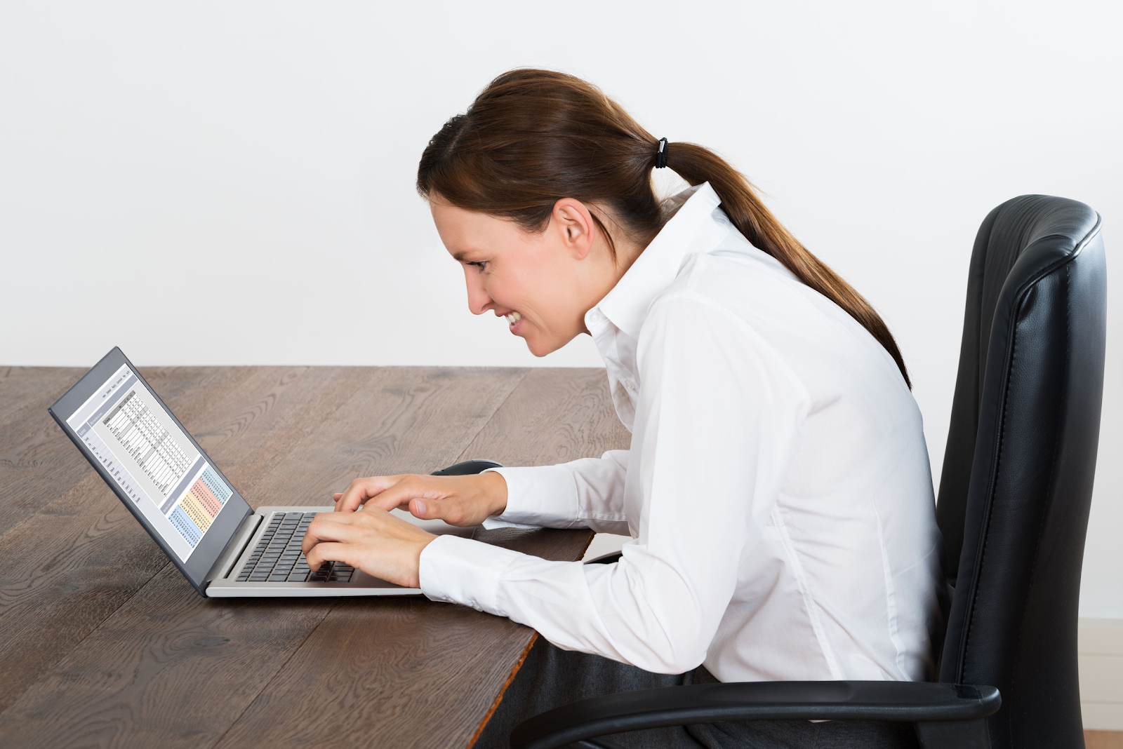 A woman hunched over the table working on her laptop